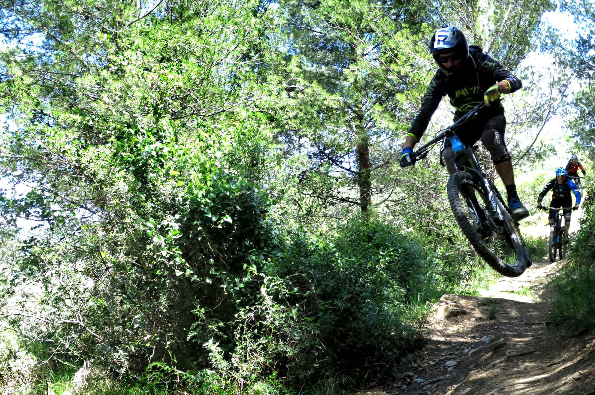 Bikers in mountain bike in discesa nelle verdi colline liguri